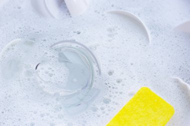 Dishes and bowls in water and bubbles of dishwashing liquid