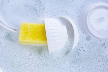 Dishes and bowls in water and bubbles of dishwashing liquid
