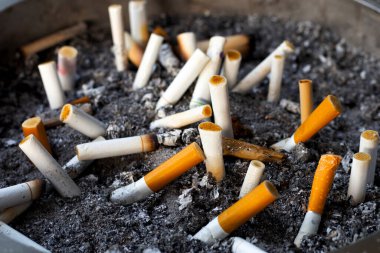 Cigarettes and ash on dirty sand in trash tray