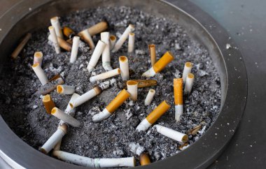 Cigarettes and ash on dirty sand in trash tray