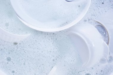 Dishes and bowls in water and bubbles of dishwashing liquid