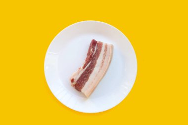 Sarı arka planda beyaz tabakta domuz eti..