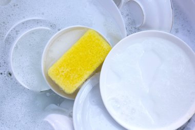 Dishes and bowls in water and bubbles of dishwashing liquid