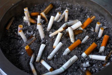 Cigarettes and ash on dirty sand in trash tray