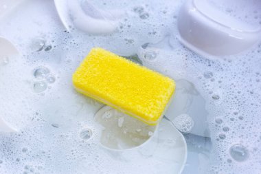 Dishes and bowls in water and bubbles of dishwashing liquid