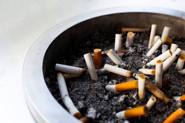 Cigarettes and ash on dirty sand in trash tray