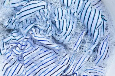 Top view of formal shirts soak in powder detergent water dissolution. Laundry concept