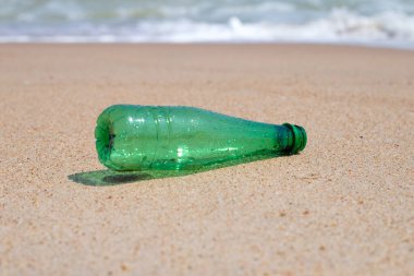 Green plastic bottle on the beach