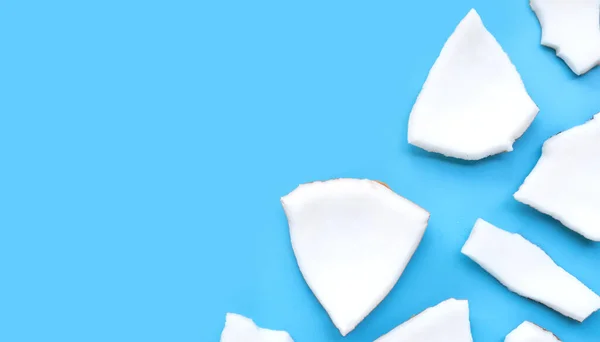 stock image Coconut cut pieces on blue background. Top view