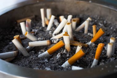 Cigarettes and ash on dirty sand in trash tray