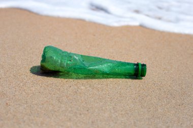 Green plastic bottle on the beach