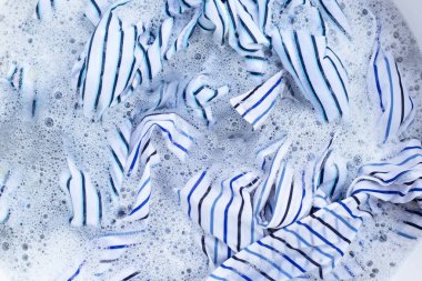 Top view of formal shirts soak in powder detergent water dissolution. Laundry concept