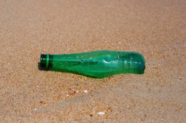 Green plastic bottle on the beach