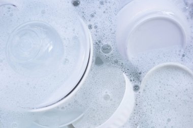 Dishes and bowls in water and bubbles of dishwashing liquid
