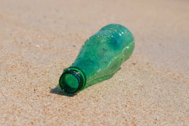 Green plastic bottle on the beach