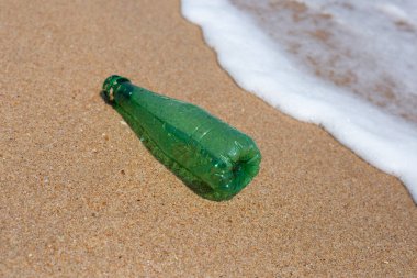 Green plastic bottle on the beach
