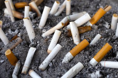 Cigarettes and ash on dirty sand in trash tray