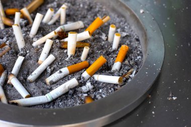 Cigarettes and ash on dirty sand in trash tray