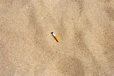 Cigarette butt on sandy beach