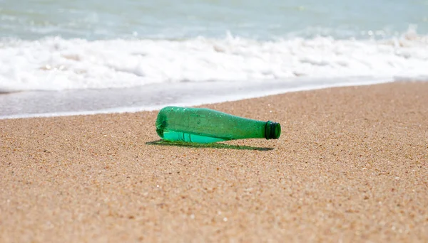 stock image Green plastic bottle on the beach