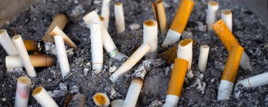 Cigarettes and ash on dirty sand in trash tray