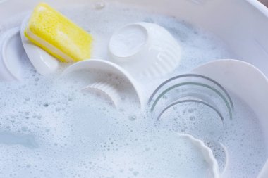 Dishes and bowls in water and bubbles of dishwashing liquid