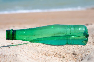 Green plastic bottle on the beach