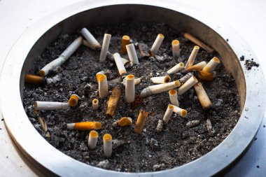 Cigarettes and ash on dirty sand in trash tray