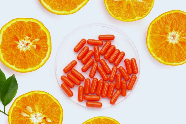 Vitamin C pills with  fresh orange citrus fruit isolated on white background.