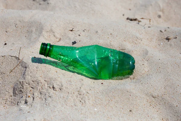 Green plastic bottle on the beach