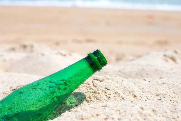 Green plastic bottle on the beach