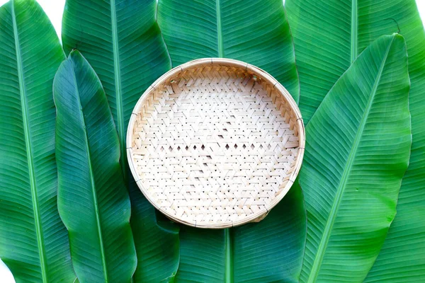 stock image Empty wooden bamboo weaves plate on banana leaves background. Top view
