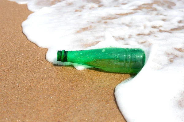 Green plastic bottle on the beach