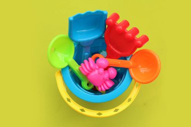Plastik oyuncaklar, kovadaki kürekler yeşil arka planda kum için. Yaz arkaplanı kavramı