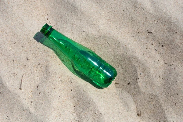 Green plastic bottle on the beach