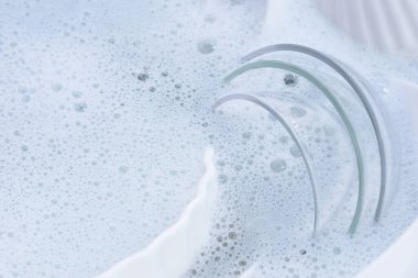 Dishes and bowls in water and bubbles of dishwashing liquid