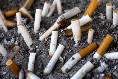 Cigarettes and ash on dirty sand in trash tray