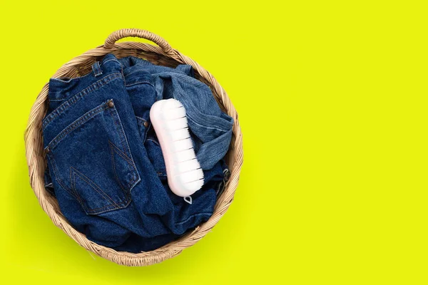 Jeans in laundry basket on green background.