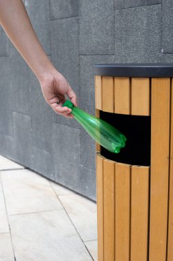 Boş plastik şişeyi geri dönüşüm çöpüne atmak.