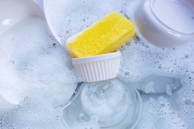 Dishes and bowls in water and bubbles of dishwashing liquid