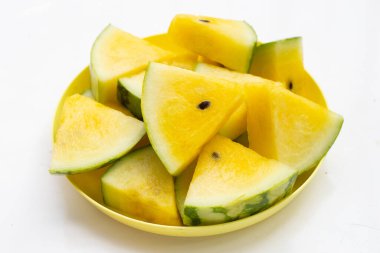 Beyaz zemin üzerinde tabakta sarı karpuz dilimleri.