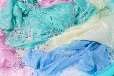 Giysiler toz deterjana batırılmış. Su çözünmüş, renkli giysiler yıkanmış.