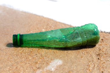 Green plastic bottle on the beach
