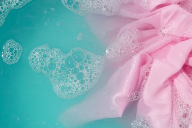 Giysiler toz deterjana batırılmış. Su çözünmüş, renkli giysiler yıkanmış.