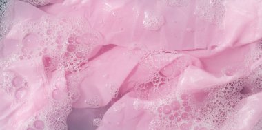 Giysiler toz deterjana batırılmış. Su çözünmüş, renkli giysiler yıkanmış.