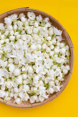 Tayland yasemin çiçeği, sarı arka planda bambu dokuma tabağı.