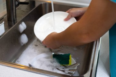 Mutfak odasında bulaşık yıkayan adam.