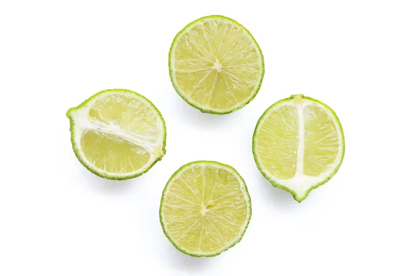 stock image Ripe limes with green leaves on white background.