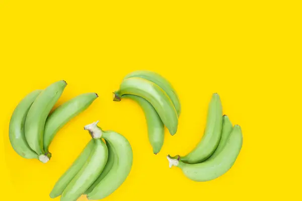 Green banana on yellow background