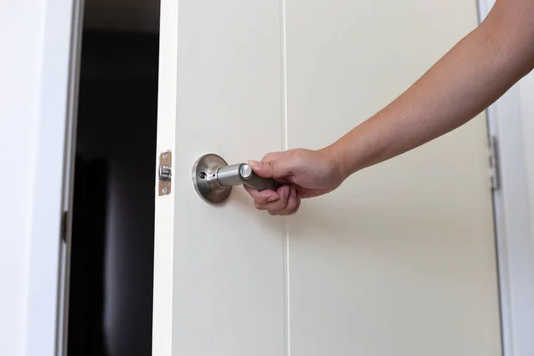 The man\'s hand is opening the door of the room.